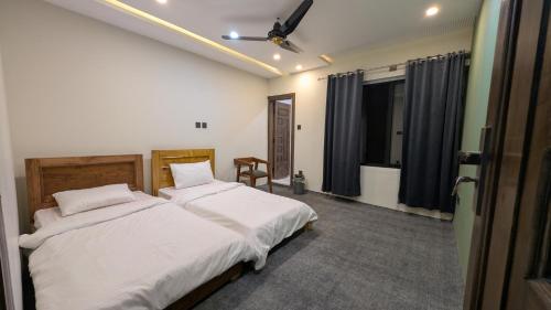 a bedroom with two beds with white sheets at PYRAMID LODGE in Skardu