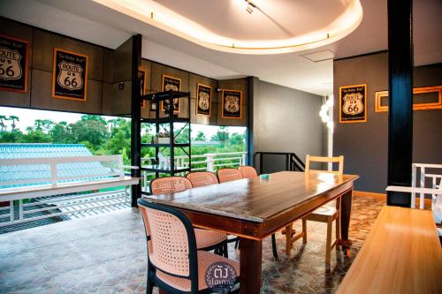 a dining room with a wooden table and chairs at ตัง โฮเทล in Ban Rai Som