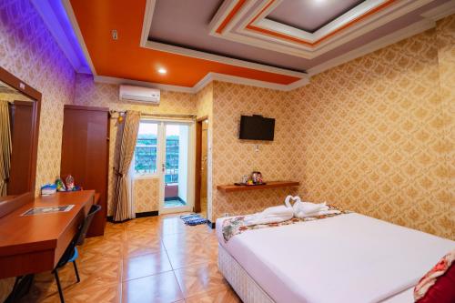 una camera da letto con un letto, una scrivania e una televisione di Grand Dream Cita Mandiri Syariah a Batu