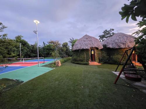 a resort with a tennis court and two huts at King Bavi Resort in Ba Vì