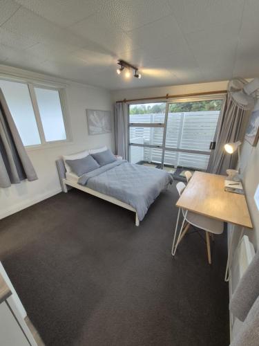 Un dormitorio con una cama y una mesa y ventanas. en Studio Parahaki, en Whangarei