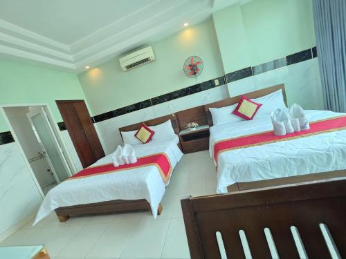 a bedroom with two beds with white and red pillows at Khách sạn Trường Sơn in Ho Chi Minh City