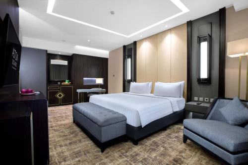 a bedroom with a bed and a couch and a chair at Aston Sidoarjo City Hotel & Conference Center in Sidoarjo