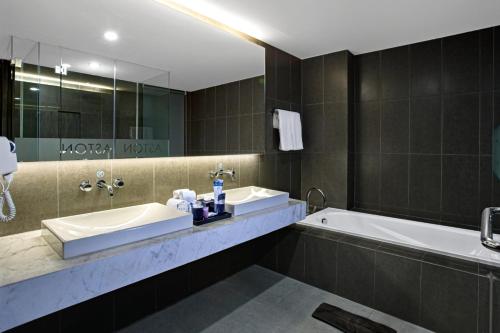 a bathroom with a tub and a sink and a mirror at Aston Sidoarjo City Hotel & Conference Center in Sidoarjo