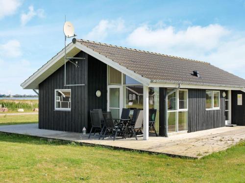 a black house with a deck and chairs on it at 8 person holiday home in Storvorde-By Traum in Langesminde