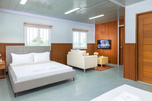 a bedroom with a bed and a couch and a television at Casa Verde in Lubao