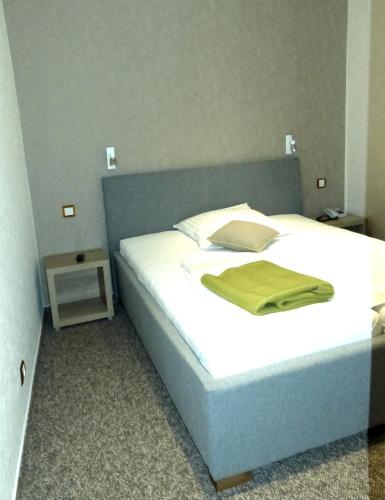 a bedroom with a bed with a green blanket on it at Hotel Aquarius Braunschweig in Braunschweig