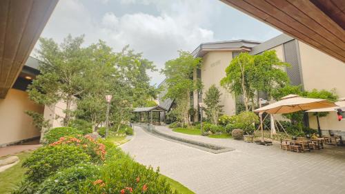 a courtyard of a building with an umbrella and flowers at Lynn Times Thanh Thuy Onsen Hot Spring in La Phu