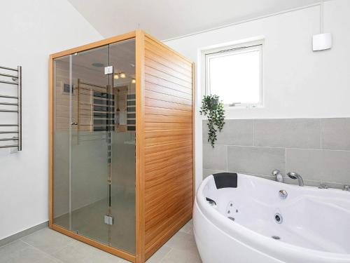 a bathroom with a tub and a glass shower at Modern Retreat with Spa - By Traum Ferienwohnungen in Løkken