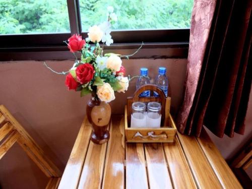 a vase with flowers on a table next to a window at Tai Asean House in Udon Thani