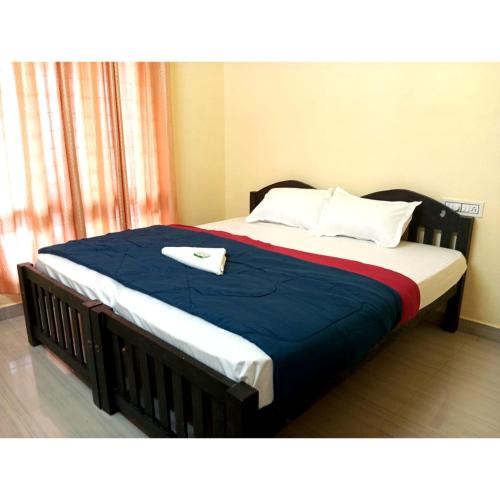a large bed with a blue blanket and white pillows at Greens Vagamon in Vagamon