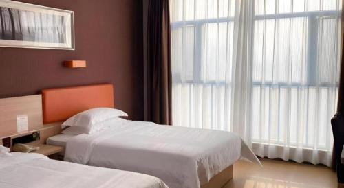 a hotel room with two beds and a window at 7Days Premium Yichang Railway Station East in Yichang