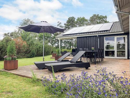 a deck with chairs and an umbrella and a table at 10 person holiday home in Hadsund in Hadsund