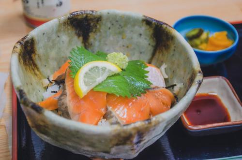 a bowl of food with fish and a lemon on it at 佐渡島 築120年の古民家一棟貸切 河崎浪漫館 囲炉裏体験 檜風呂-蔵サウナ完備 in Sado