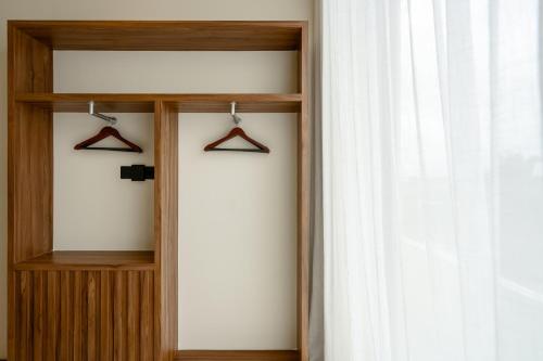 a wooden closet with hangers and a window at Sore Escape Tumbak Bayuh by Betterplace in Tumbak Bayuh