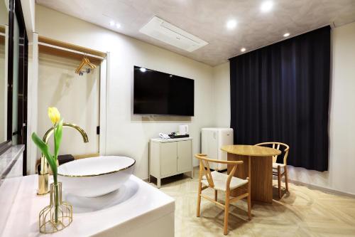 a bathroom with a television and a table and chairs at Chuncheon Intro Family hotel in Chuncheon