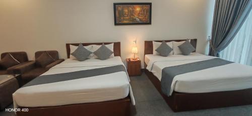 a hotel room with two beds and a couch at Nimith Hotel & Restaurant in Phnom Penh