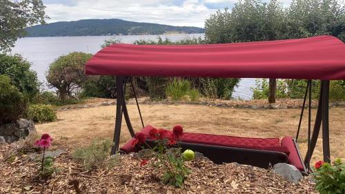 a red couch sitting under a red umbrella at Beachbreeze Panoramic Oceanview 4BR 3BA Romantic Sunrise & Celestial Views in Mill Bay