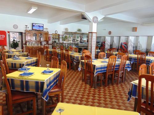 a restaurant with yellow and blue tables and chairs at Residencia Beira Baixa in Monfortinho