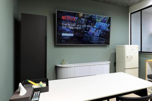 a kitchen with a white table and a tv on the wall at Chuncheon Intro Family hotel in Chuncheon