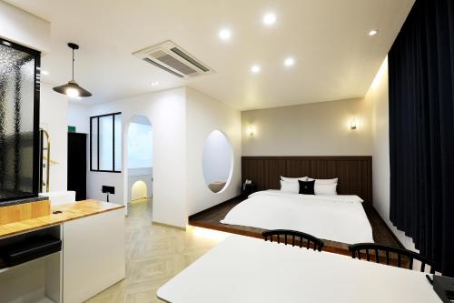 a bedroom with two beds and a kitchen with a window at Chuncheon Intro Family hotel in Chuncheon