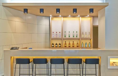 a bar with four stools in front of a counter at NH Ciudad de Zaragoza in Zaragoza