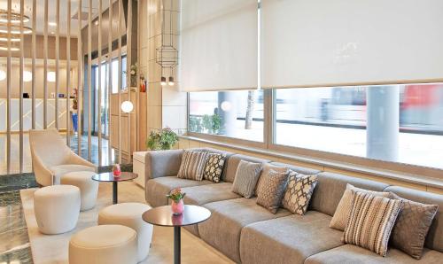 a living room with a couch and tables at NH Ciudad de Zaragoza in Zaragoza
