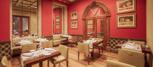 a restaurant with red walls and tables and chairs at NH Collection Vigo in Vigo