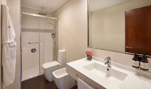 a bathroom with a sink and a toilet and a mirror at NH Collection Vigo in Vigo
