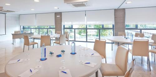 a conference room with tables and chairs and windows at NH Ciudad de Zaragoza in Zaragoza