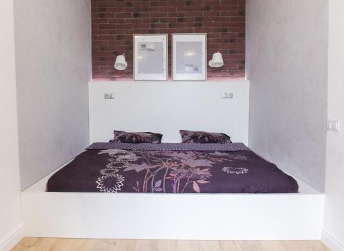 un letto in una camera bianca con tre immagini sul muro di Apartments on Belinskogo ulitsa a San Pietroburgo