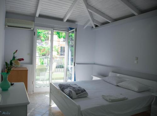 biała sypialnia z łóżkiem i oknem w obiekcie Steven w mieście Vasiliki