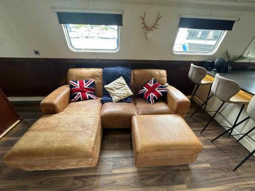 a living room with a brown couch with pillows at Selene Unique Luxury Houseboat Experience in Chertsey
