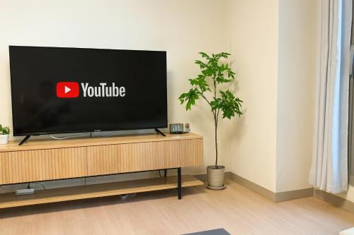 a flat screen tv sitting on top of a wooden entertainment center at E 2BR 60m2 Newly Built High Floor APT 2min to Hyundai Outlet Triple St 2Free Parking in Incheon