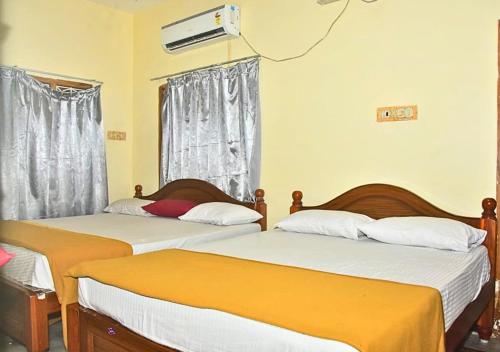 a bedroom with two beds and a window at JR Residency in Tirukkadaiyūr