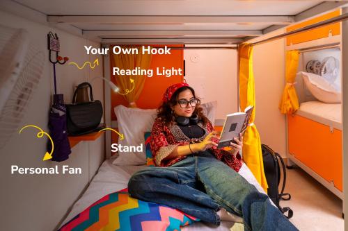 a woman sitting on a bed with a laptop at goSTOPS PLUS Kasol, Suma Ropa in Kasol