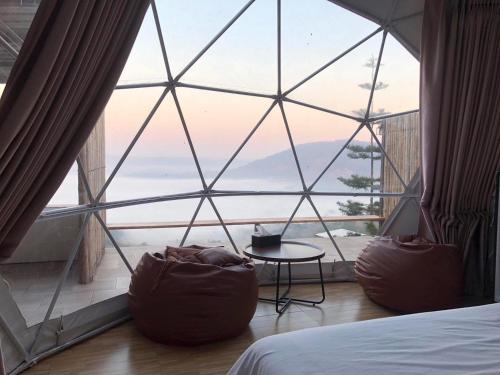 a bedroom with a large window with a bed and a table at ร่มการเวก เขาค้อ ROM KARAVEK Khao Kho Resort in Khao Kho