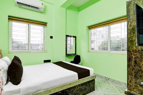 a green bedroom with a bed and two windows at Super Collection O Shyam Bazar Metro Station in Kolkata