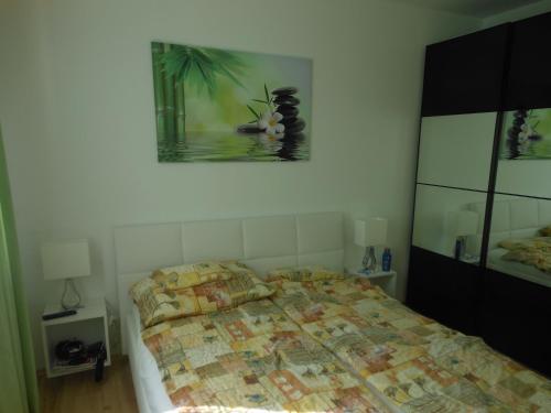 a bedroom with a bed and a painting on the wall at Galerius Golden Beach Apartment in Siófok