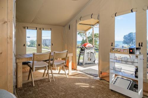 a caravan with a desk and chairs in a room at Ōhope Beach TOP 10 Holiday Park in Ohope Beach