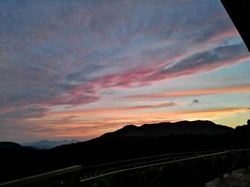 a view of a sunset with mountains in the background at Minamiaso Nobara Inn in Minami Aso