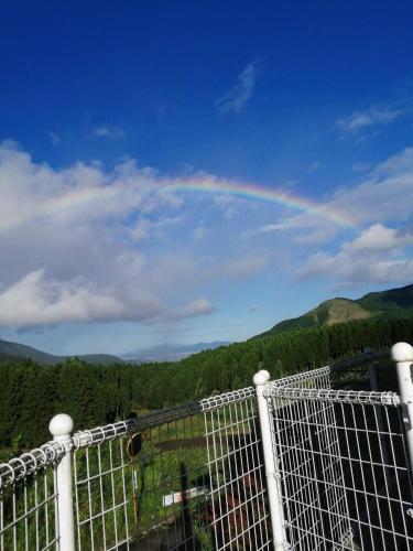 a rainbow in the sky behind a fence at Minamiaso Nobara Inn in Minami Aso
