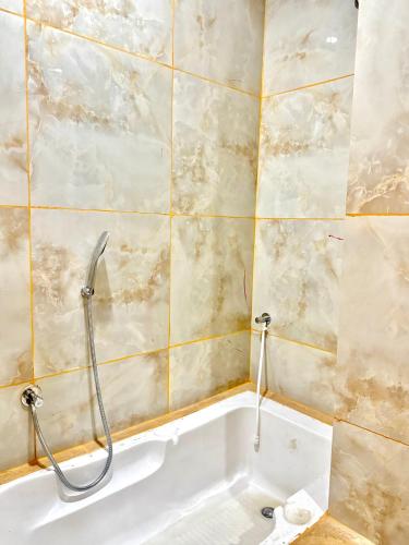 a bath tub in a bathroom with a tiled wall at Hotel The Argal By Basotel, Vijay Nagar in Indore