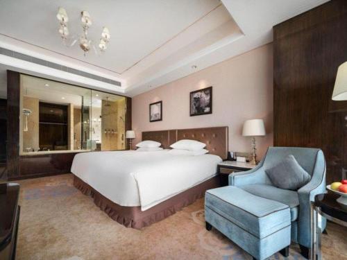 a bedroom with a large bed and a blue chair at Dongwu New Century Grand Hotel Huzhou in Huzhou