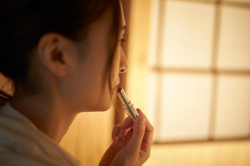 a woman brushing her teeth while looking in a window at KARASUYA GuestHouse in Takasaki