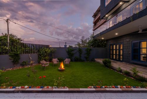 a backyard with a fire pit in the grass at SaffronStays Tarangini by Ganges in Rishīkesh