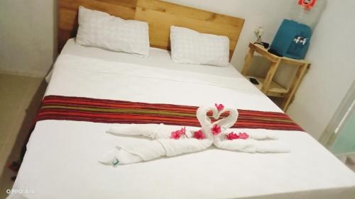 a bed with white towels and a pink ribbon on it at Twins Homestay ekas in Pulau Gilkaliantan