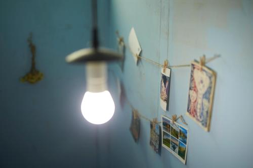 a light bulb hanging from a blue wall with pictures at KARASUYA GuestHouse in Takasaki