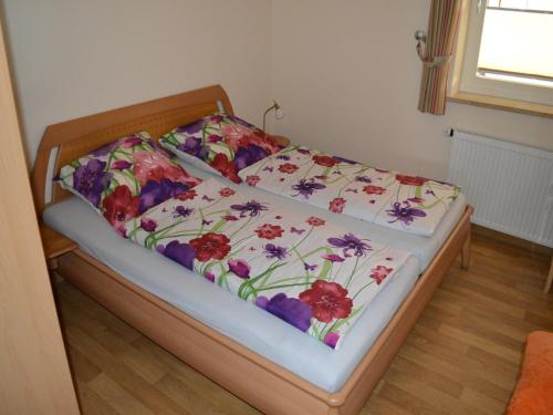 a bed with a floral comforter on it at Lindern Woodland Mansion in Werlte