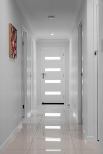 an empty hallway with white walls and white doors at Whispering Pines - Stylish 3BR Duplex close to M1 in Pimpama